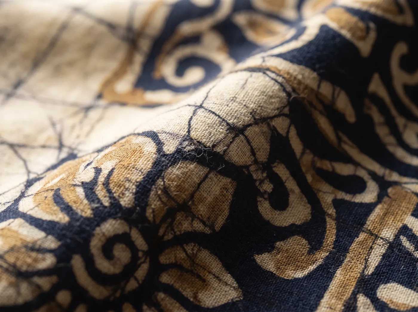 A close view of indigo batik cloth, the wax-resist crackle visible across the weave.
